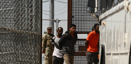 La Guardia Nacional del Ejército de Texas observa cómo migrantes suben a un autobús después de entregarse a los agentes de la Patrulla Fronteriza de Aduanas.