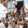 Un hombre arroja una bolsa de arroz a una multitud de víctimas del terremoto reunidas para la distribución de alimentos y agua en el cruce de “4 Chemins” en Les Cayes, Haití. Bandas criminales fuertemente armadas controlan varios suburbios de Puerto Príncipe, donde llevan a cabo secuestros y dificultan la entrega de ayuda humanitaria. / AFP