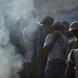 Personas miran cuerpos en la calle de miembros de bandas quemados en Puerto Príncipe.
