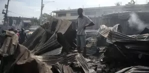 Un vendedor observa a los bomberos trabajar para extinguir un incendio en el mercado Shada en el área de Petion-ville en Puerto Príncipe, ayer.