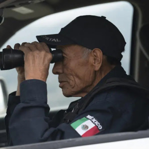 Nefi de Aquino, quien trabaja como oficial de policía y también vigila la actividad del Popocatépetl, observa el volcán a través de sus binoculares desde Santiago Xalitzintla, México, el jueves 25 de mayo de 2023.