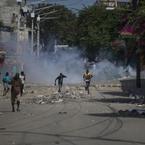 Manifestantes corren después de que la policía arrojara gases lacrimógenos durante una protesta para exigir la renuncia del primer ministro Ariel Henry, el lunes 3 de octubre de 2022, en la zona de Petion-Ville, en Puerto Príncipe, Haití.