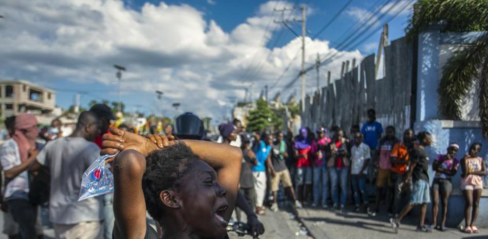 Una mujer llora cerca del cuerpo de otra mujer muerta a tiros por la policía durante una protesta que exigía la renuncia del primer ministro Ariel Henry en el área de Delmas en Puerto Príncipe, Haití, el lunes 10 de octubre de 2022. (Foto AP/ Odelyn José).