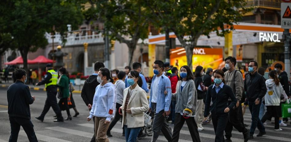 La gente cruza una calle en el distrito de Jing'an en Shanghái el 25 de octubre de 2022.

Foto: Héctor Retamal/ AFP