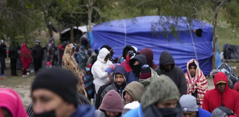 Migrantes venezolanos se forman para recibir alimentos y bebidas calientes en un campamento en la ciudad norteña de Matamoros, México,  23 de diciembre de 2022. AP