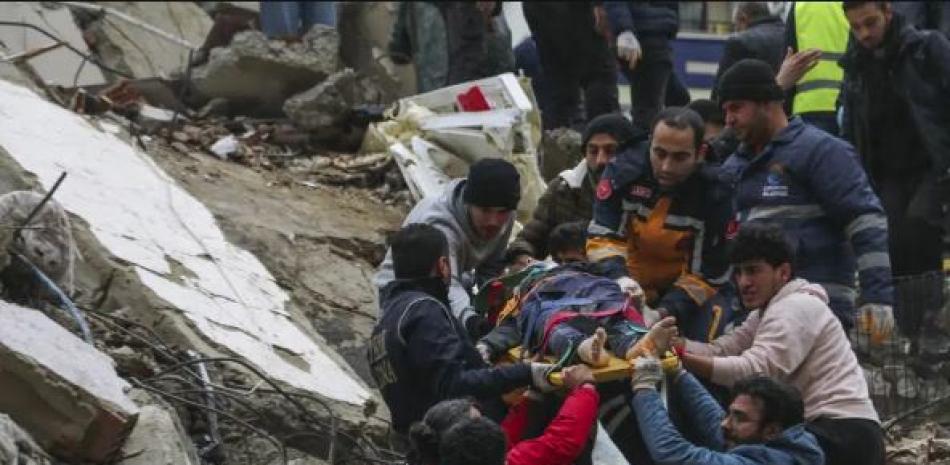 Personas y equipos de emergencia rescatan a una persona en una camilla de un edificio derrumbado en Adana, Turquía, el lunes 6 de febrero de 2023. Un poderoso terremoto derribó varios edificios en el sureste de Turquía y Siria y se temen muchas víctimas. (Agencia IHA vía AP)
