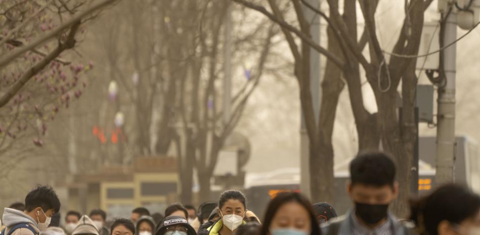 Personas con máscaras faciales caminan por una calle en el distrito comercial central de Beijing, el miércoles 22 de marzo de 2023. Una tormenta de polvo y arena hizo que los índices de calidad del aire se dispararan en la capital de China el miércoles por la mañana. (Foto AP/Mark Schiefelbein)