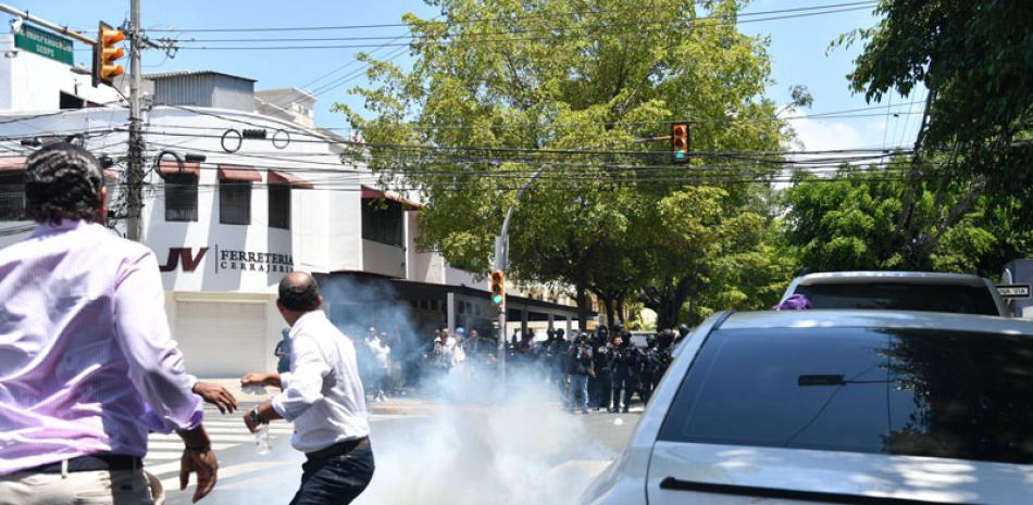 Miembros del PLD próximo a gases lacrimógenos lanzados por la policía.