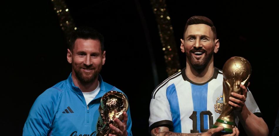La estrella del fútbol argentino Lionel Messi sostiene una réplica del trofeo de la Copa Mundial de la FIFA junto a una estatua de sí mismo durante una ceremonia en la sede de la CONMEBOL en Asunción, el lunes 27 de marzo de 2023.