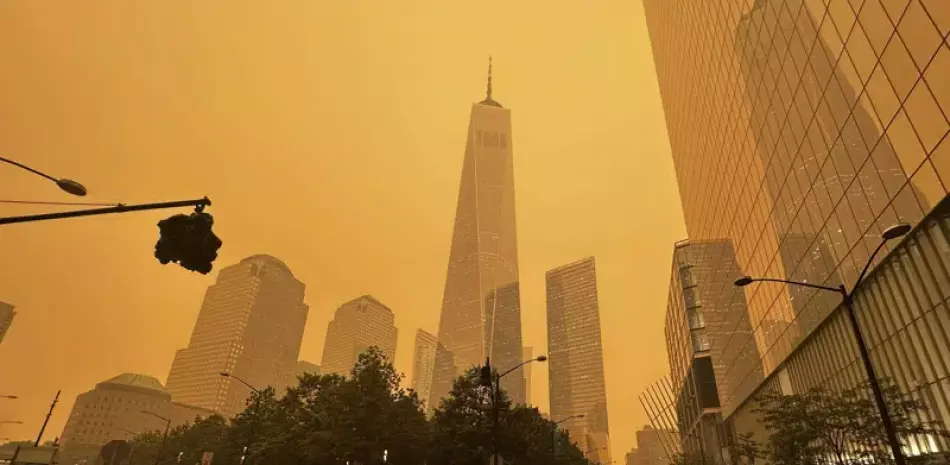 Peatones pasan junto al One World Trade Center (centro), en medio de la humareda causada por los incendios forestales en Canadá, el 7 de junio de 2023, en la Ciudad de Nueva York.