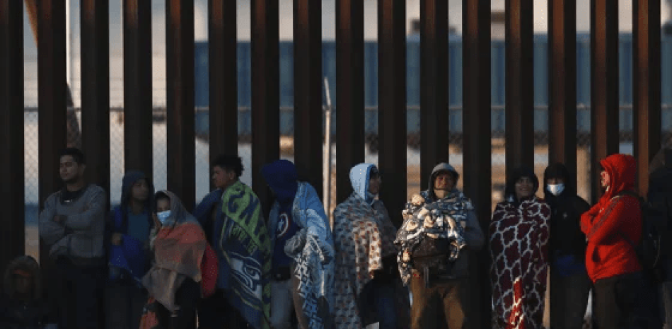 Migrantes se reúnen junto al muro fronterizo en Ciudad Juárez, México, el miércoles 21 de diciembre de 2022, al otro lado de la frontera con El Paso, Texas. Los migrantes se reunieron a lo largo del lado mexicano de la frontera sur el miércoles mientras esperaban que la Corte Suprema de los Estados Unidos decidiera si levantar las restricciones de la era de la pandemia que han impedido que muchos busquen asilo y cuándo.