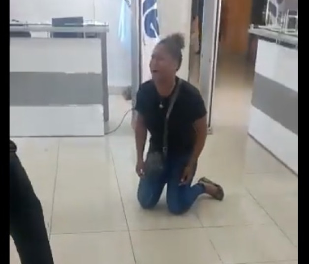 Una mujer se arrodilla en reclamo de dinero en una oficina de la ONE
