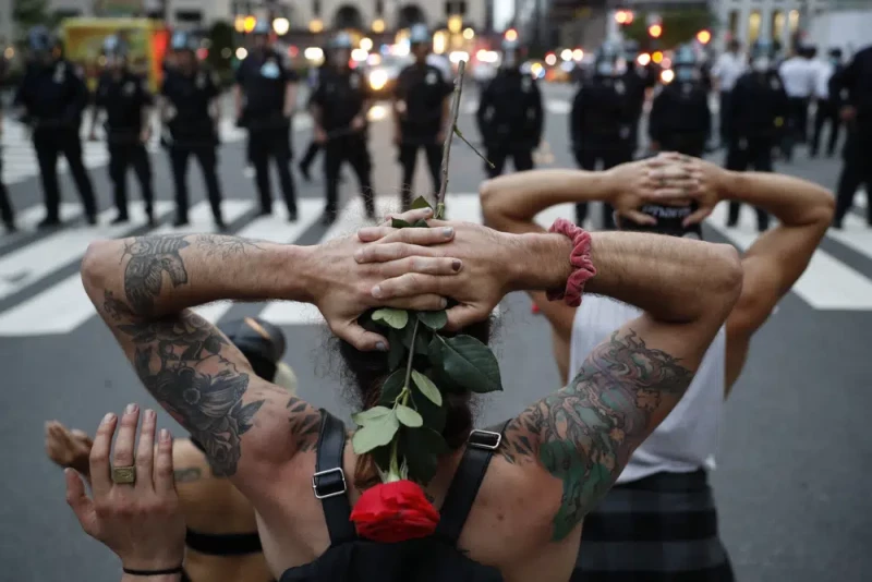 Manifestantes se arrodillan frente a agentes de la policía de Nueva York antes de ser arrestados por violar un toque de queda, el 3 de junio de 2020, en Nueva York.