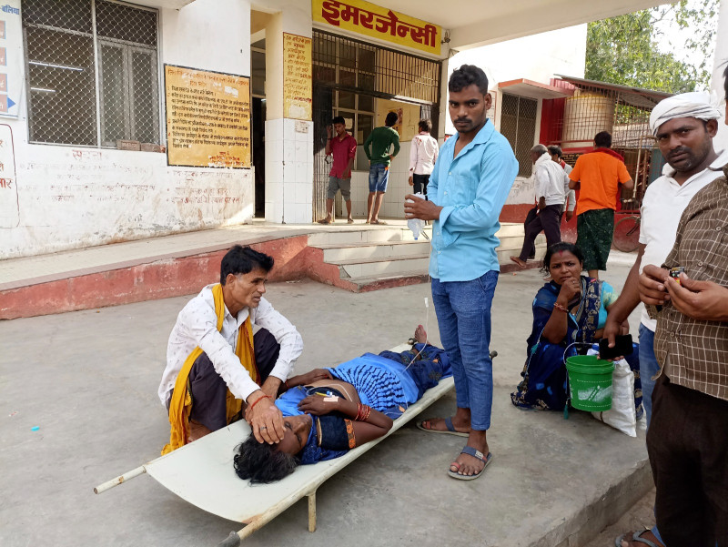 Familiares cuidan a un paciente acostado en una camilla afuera de un hospital del distrito de Ballia, en la India, el domingo 18 de junio de 2023.