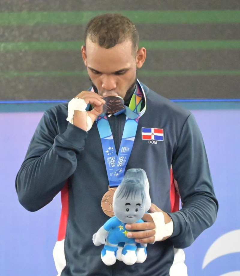 Julio Cedeño, mientras muerde su medalla en el podium.
