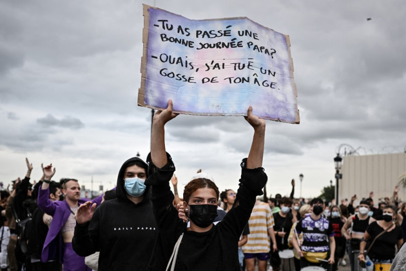 Un manifestante sostiene un cartel que dice "¿Tuviste un buen día, papá? -Sí, maté a un niño de tu edad" en Burdeos, suroeste de Francia, el 30 de junio de 2023, sobre el tiroteo de un conductor adolescente por parte de la policía francesa en un Suburbio de París.