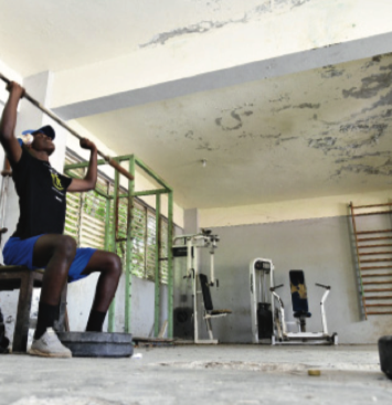 Atleta entrenando en el gimnasio deteriorado.